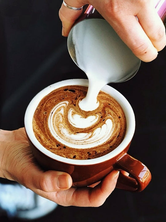 Barista pouring latte art in an ACME Classic Medium Ceramic Cup