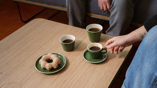 Acme Roman cups with coffee in them, and a Roman plate with a donut