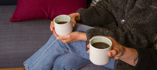 Tajimi cups being held by two people on a sofa with coffee inside the cups