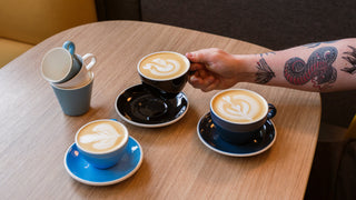 Acme cups with coffee and latte art on a table